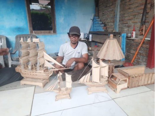 Zulfansyah bersama miniatur kapal dan lampion kayu produksi Rumah Pengrajin Bahagia di Deli Serdang. Foto: Dokumentasi Tim PKM Politeknik Negeri Medan